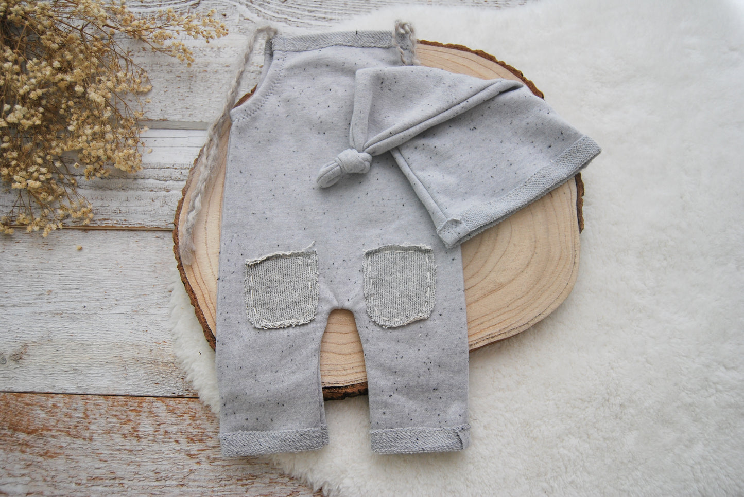 Gray baby outfit with pants and hat on a wooden surface