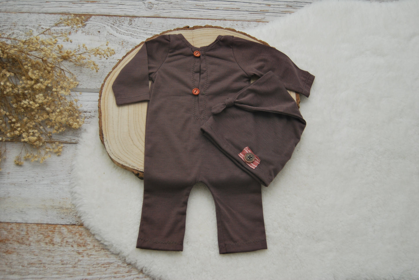 The back of a newborn boy romper with button closure and a newborn beanie