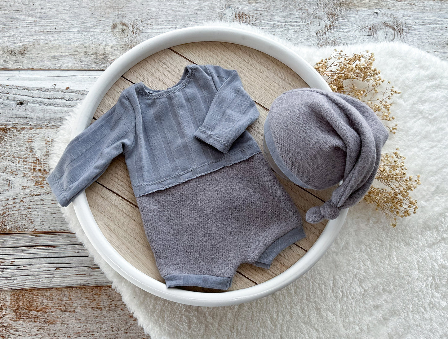 Gray baby outfit with hat in a white bowl on a wooden surface