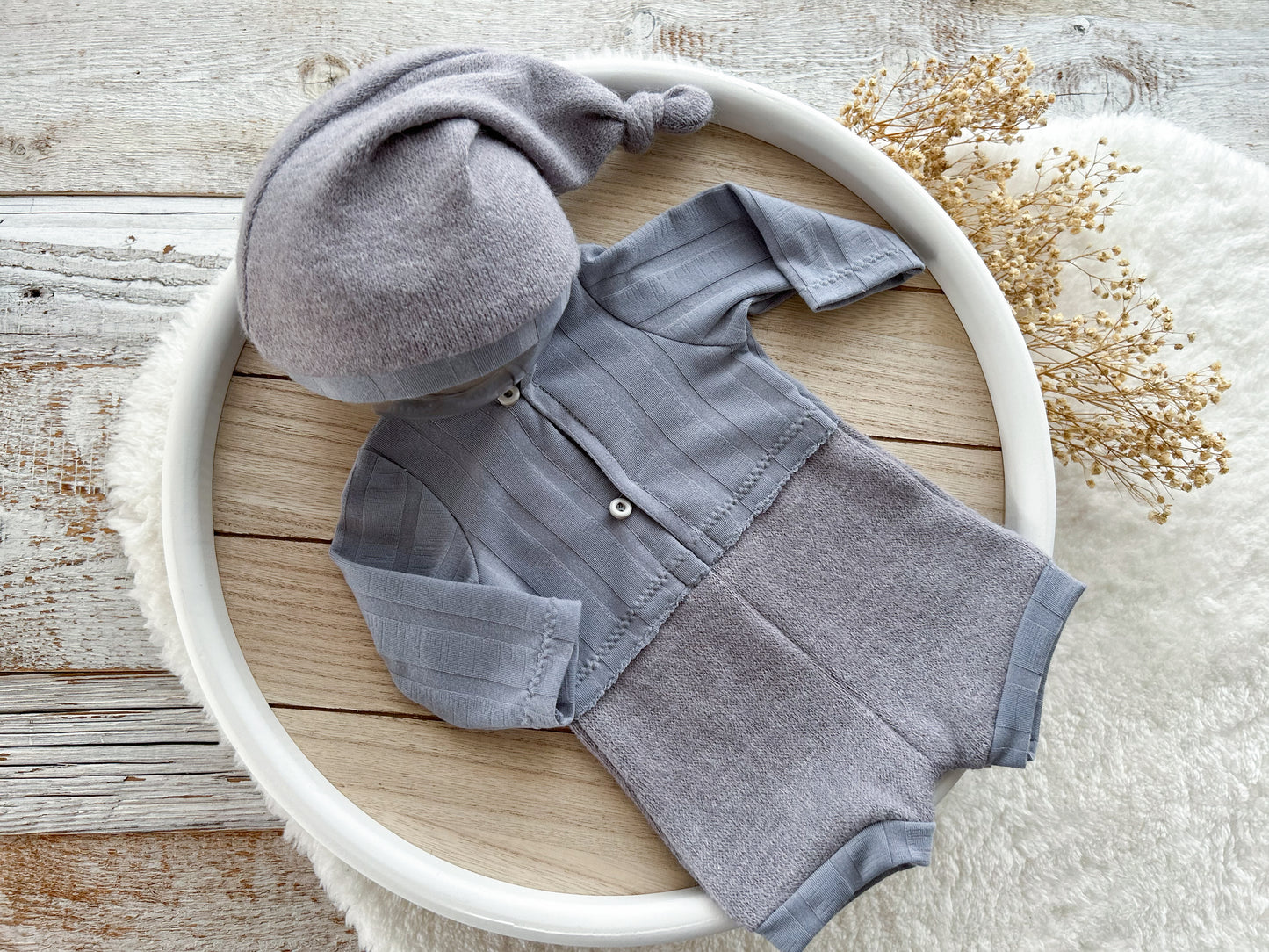 Gray baby outfit with hat on a wooden surface