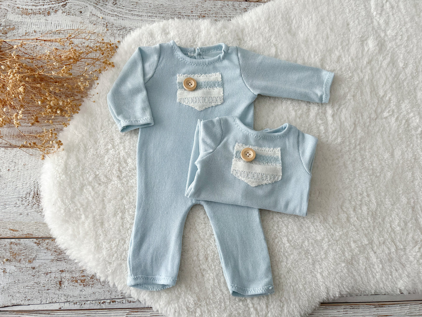Back view of the newborn romper showing buttoned opening, displayed on a wooden tray.