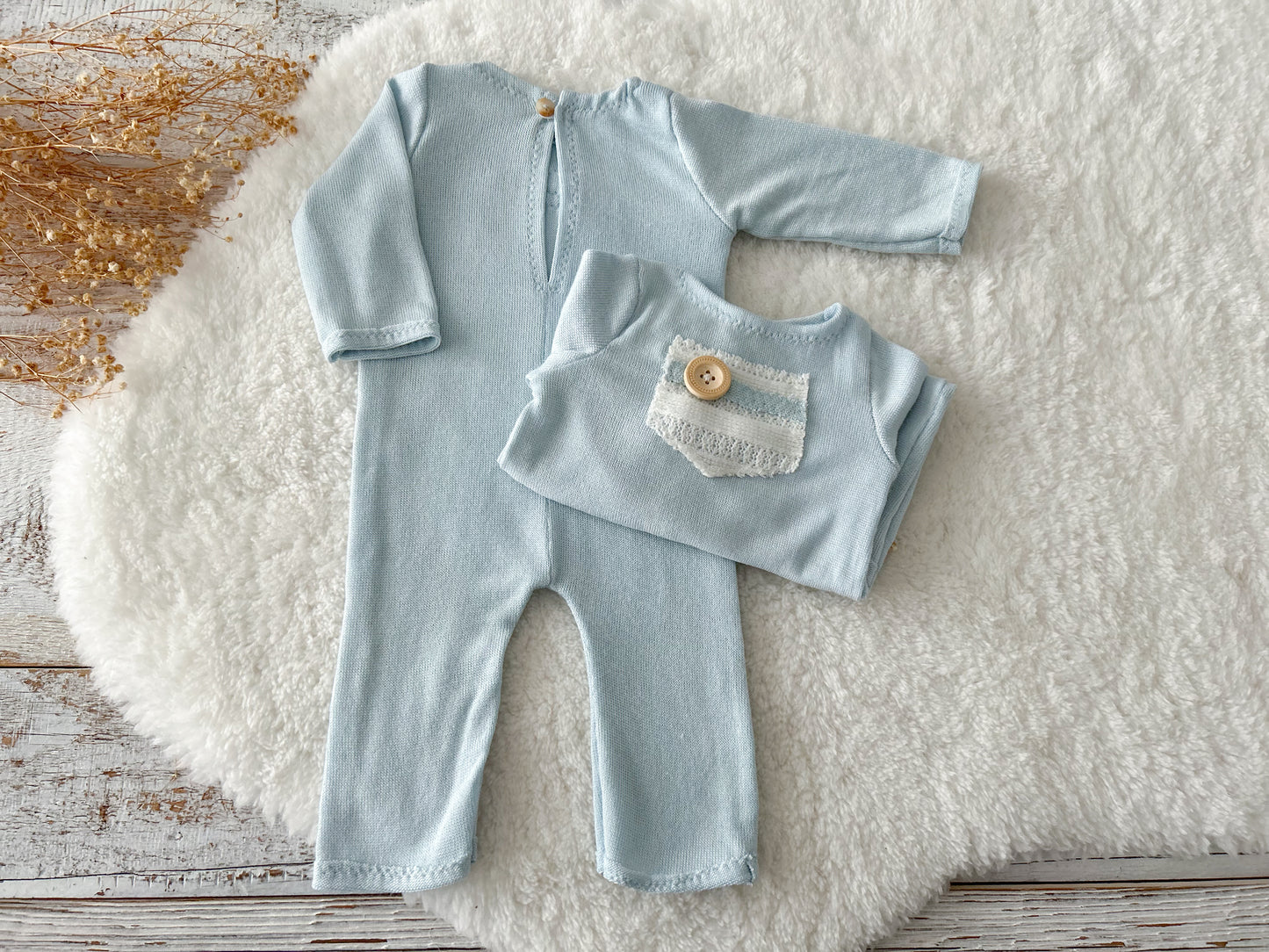 Flat lay of soft blue newborn romper and sleepy hat on fluffy background.