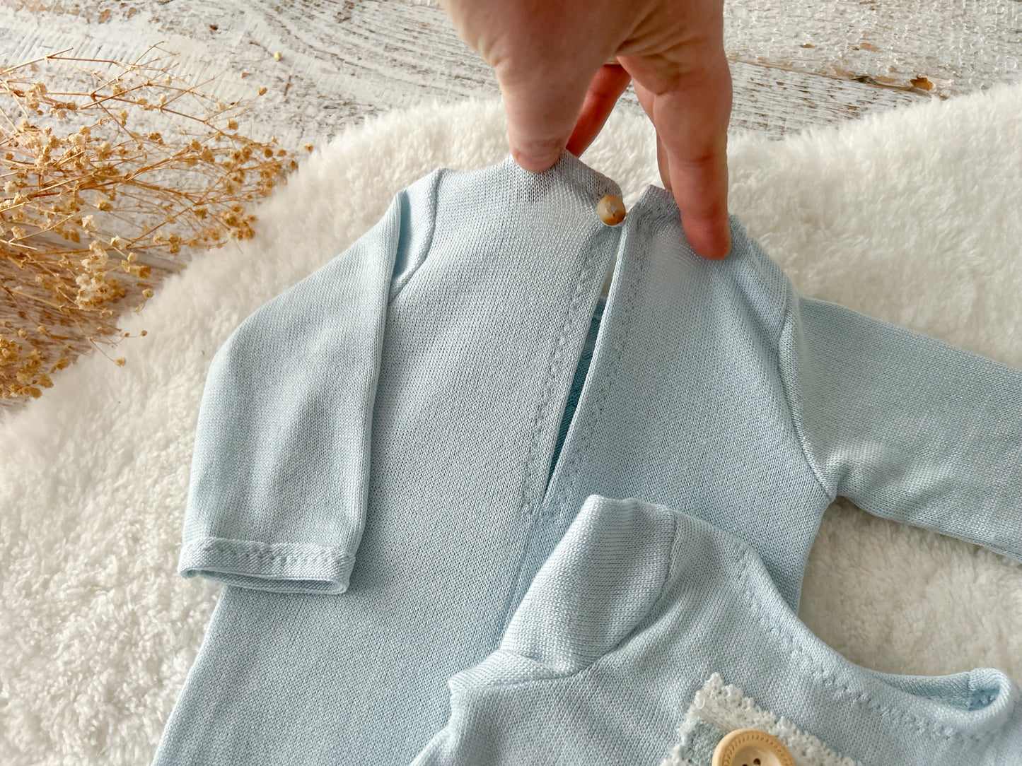 Close-up of front pocket detail on knit romper with wooden button.