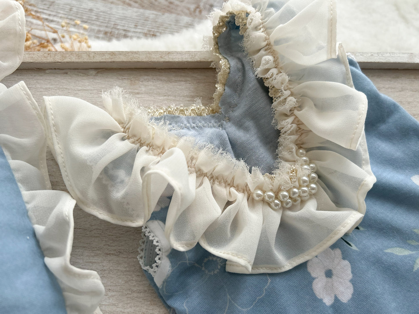 Close up on the back of the romper that has an U shape and is decorated with ruffles and pearl beads.