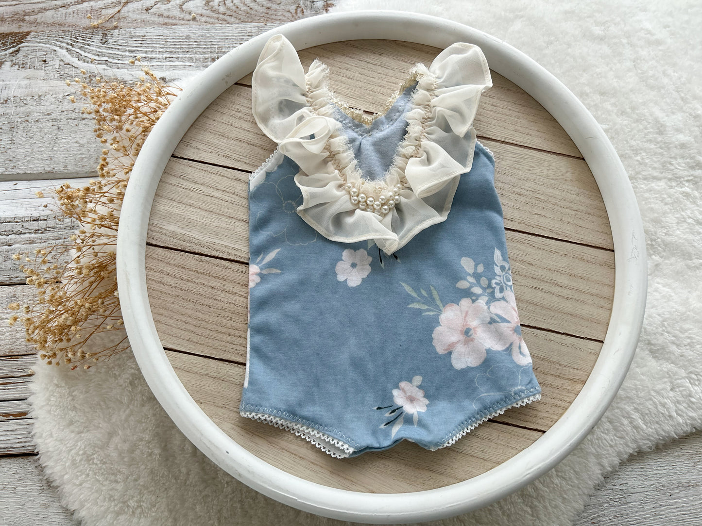 The back of the newborn romper displayed on a round wooden tray.
