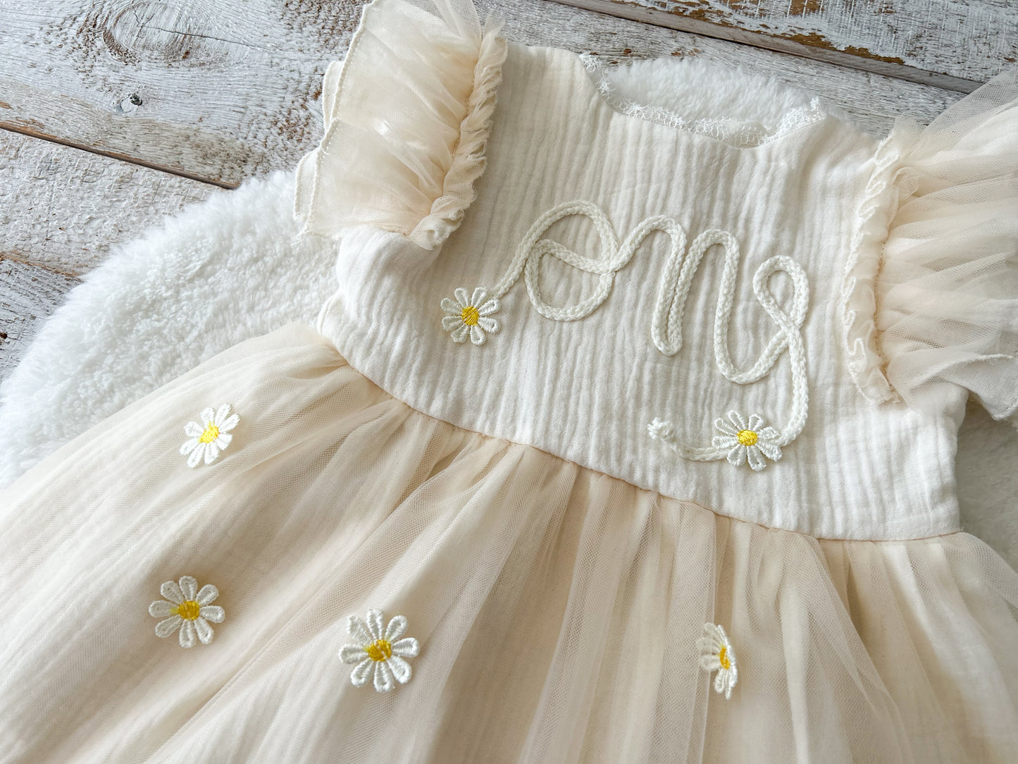 Beige dress with floral details on a wooden surface