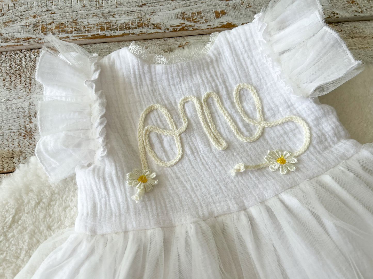 White dress with floral embroidery on a wooden surface