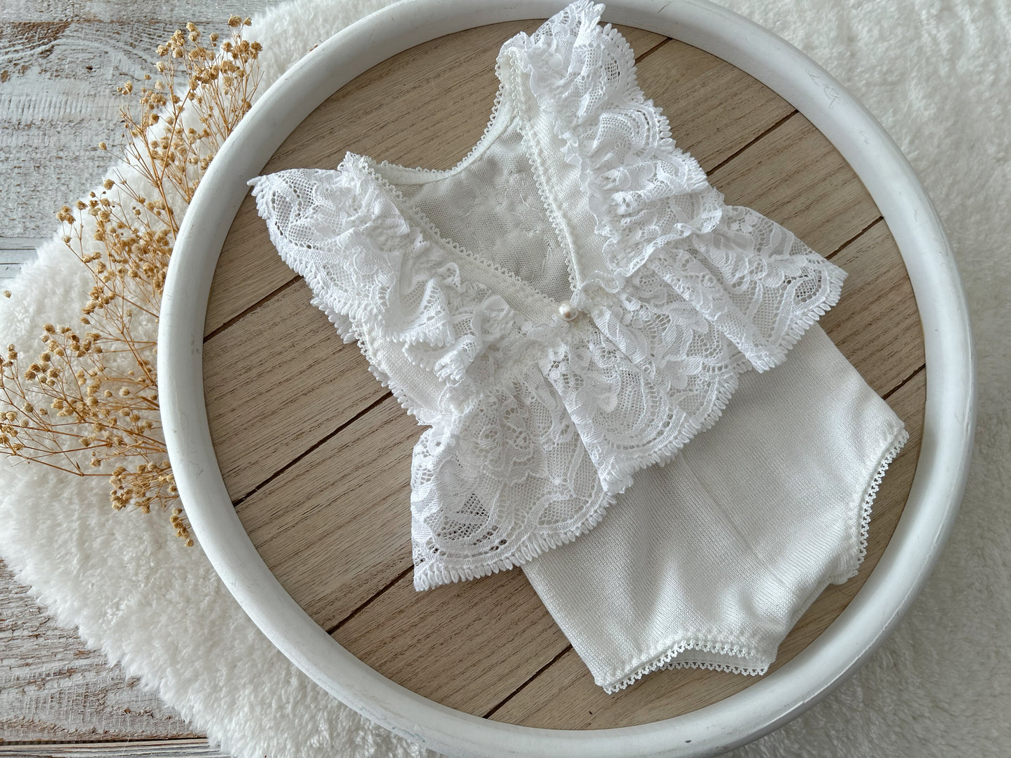 Newborn lace romper made of white lace with floral texture