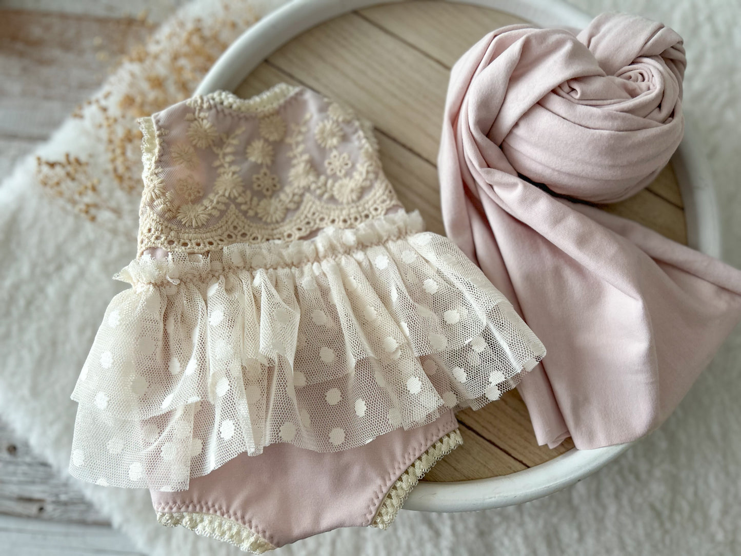 Flat lay of blush pink romper with matching wrap – styled setup