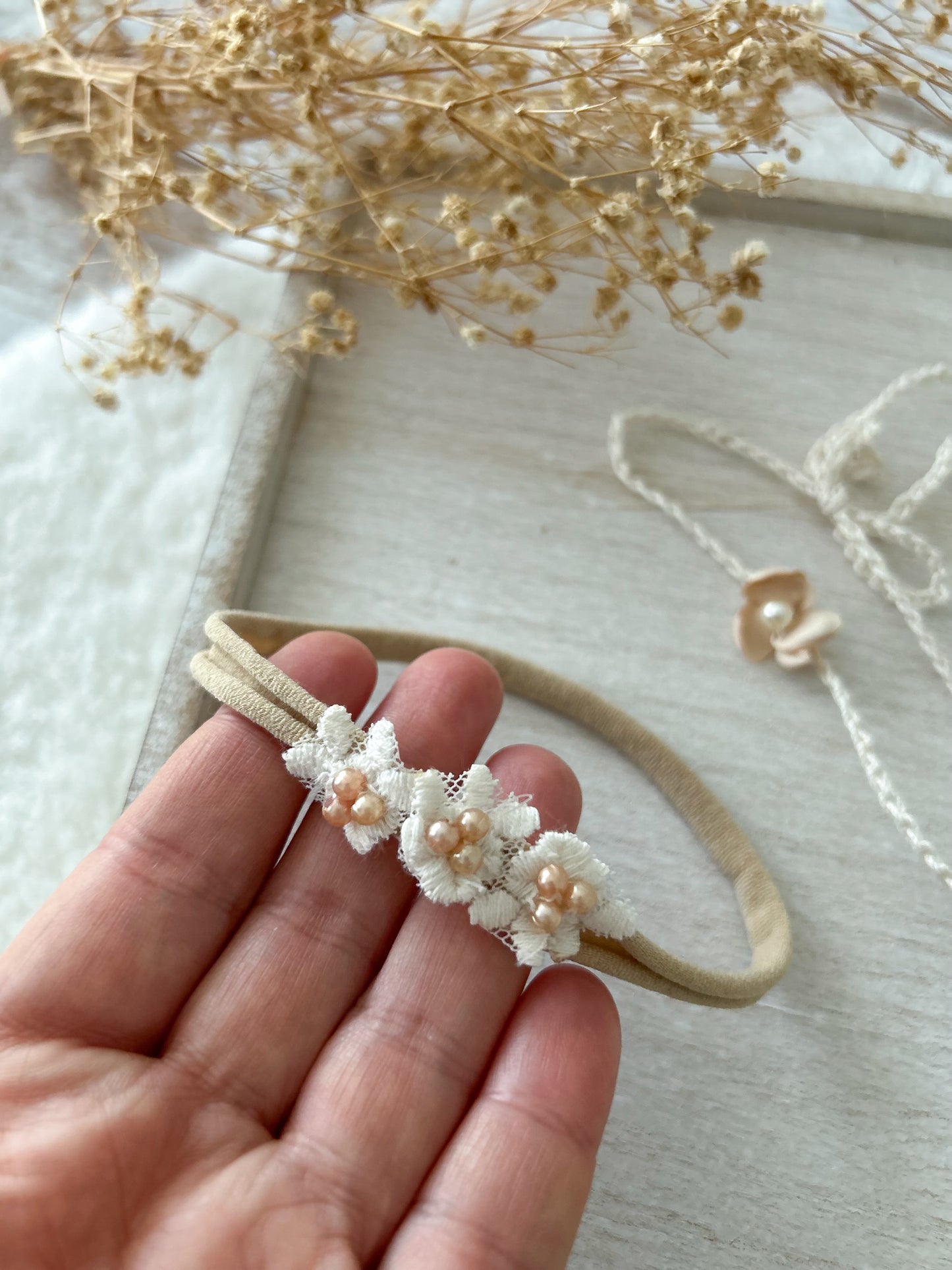 Close-up of delicate baby headband with soft band and floral appliqué, perfect for photography sessions.