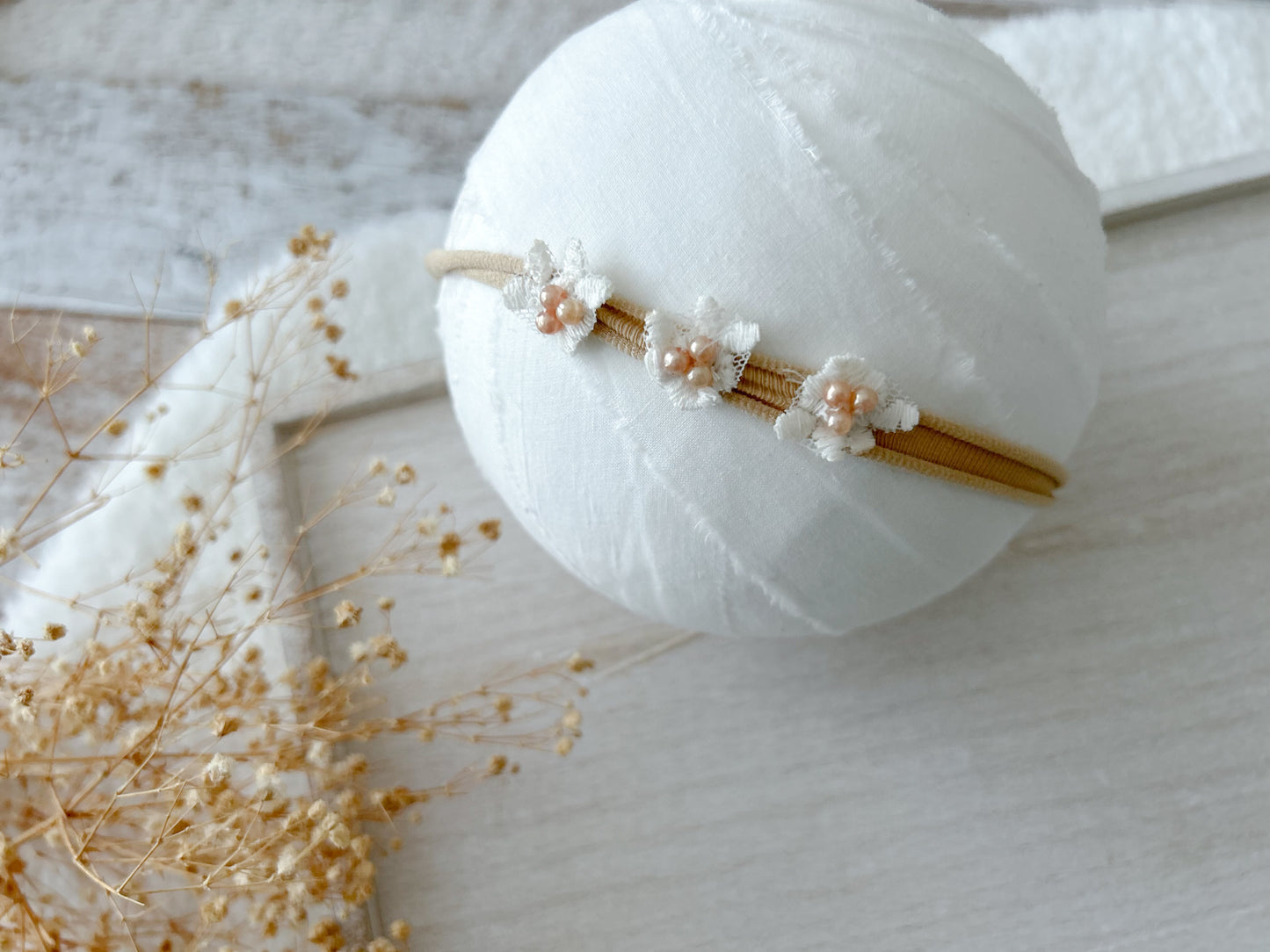 Newborn photography headbands in neutral tones with vintage-inspired floral and pearl details.