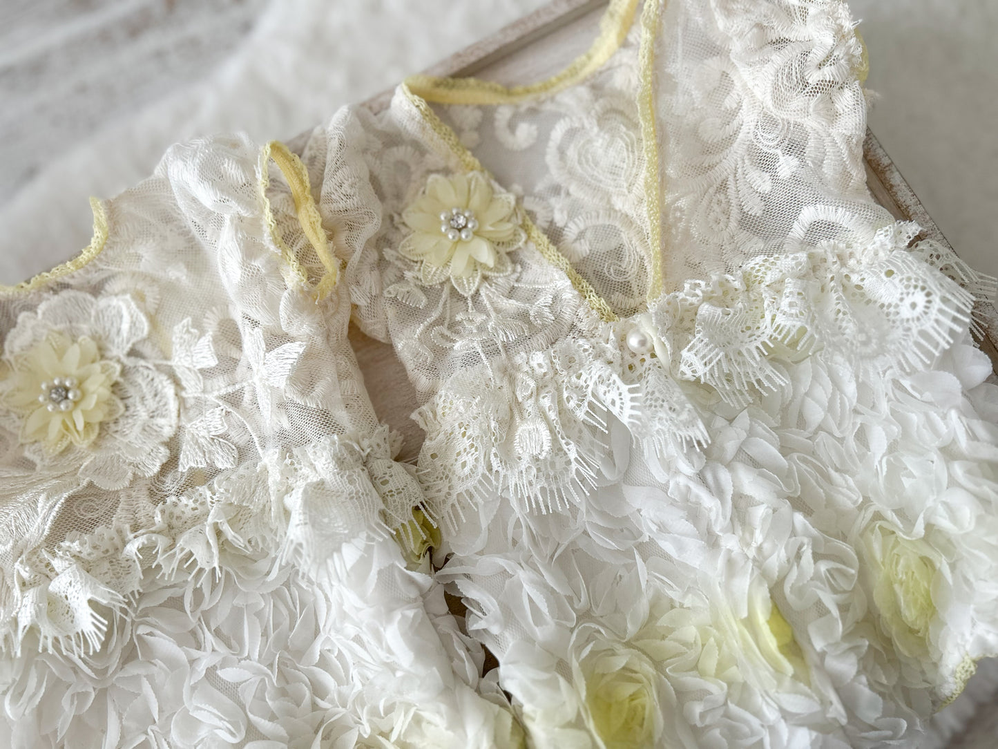 White lace newborn photo outfit with floral details on a light background