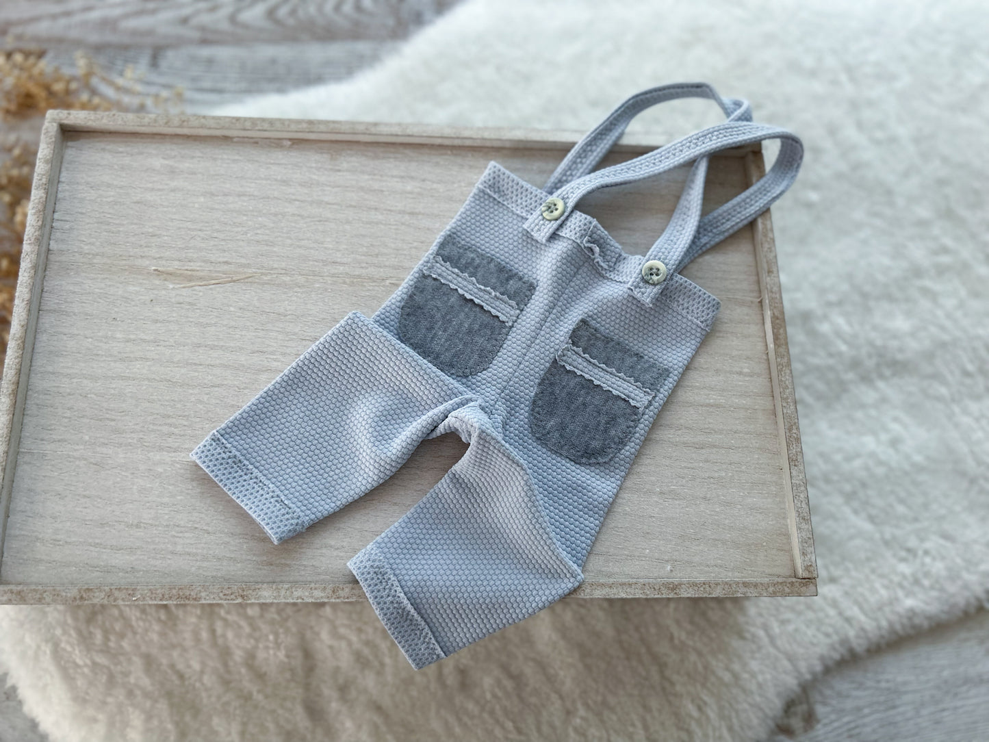 Light blue baby pants with gray accents on a wooden surface