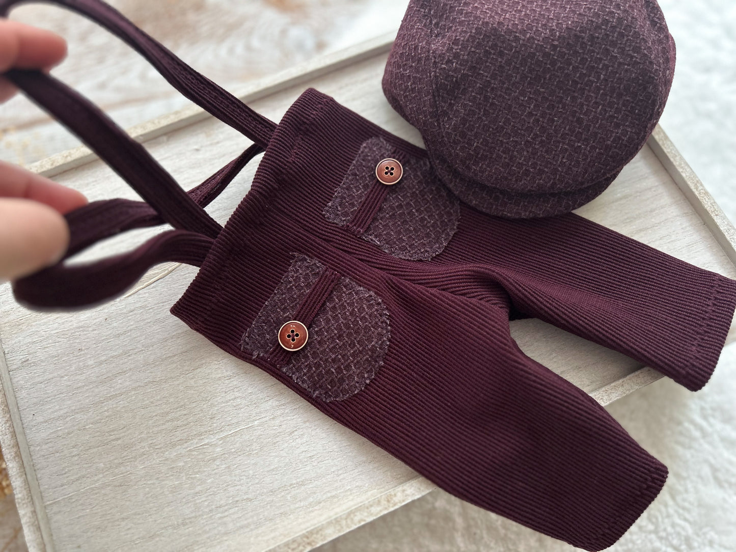 Purple baby outfit with buttons on a light wooden surface