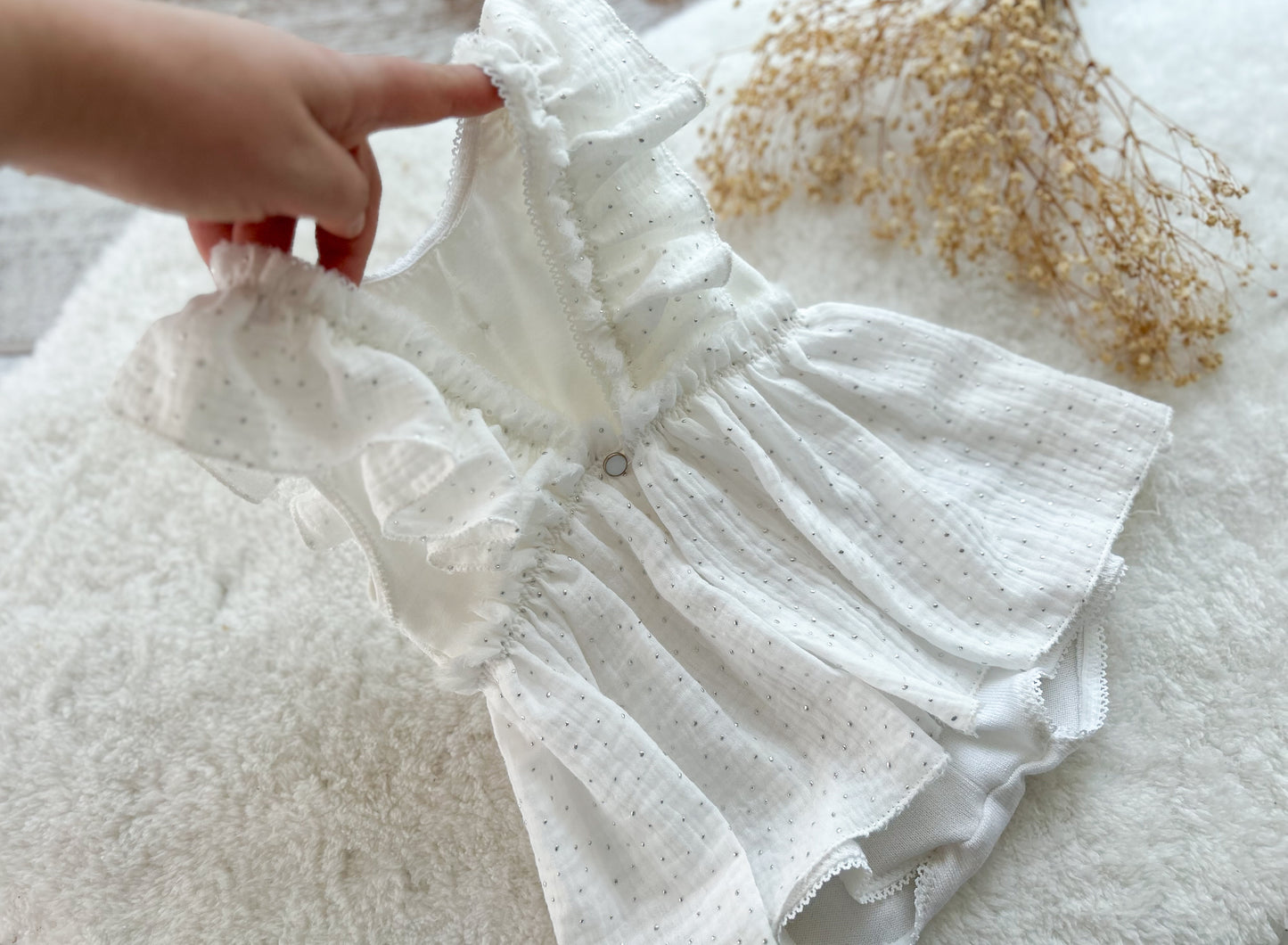 Close-up of a white textured fabric with a hand holding it, on a light background.