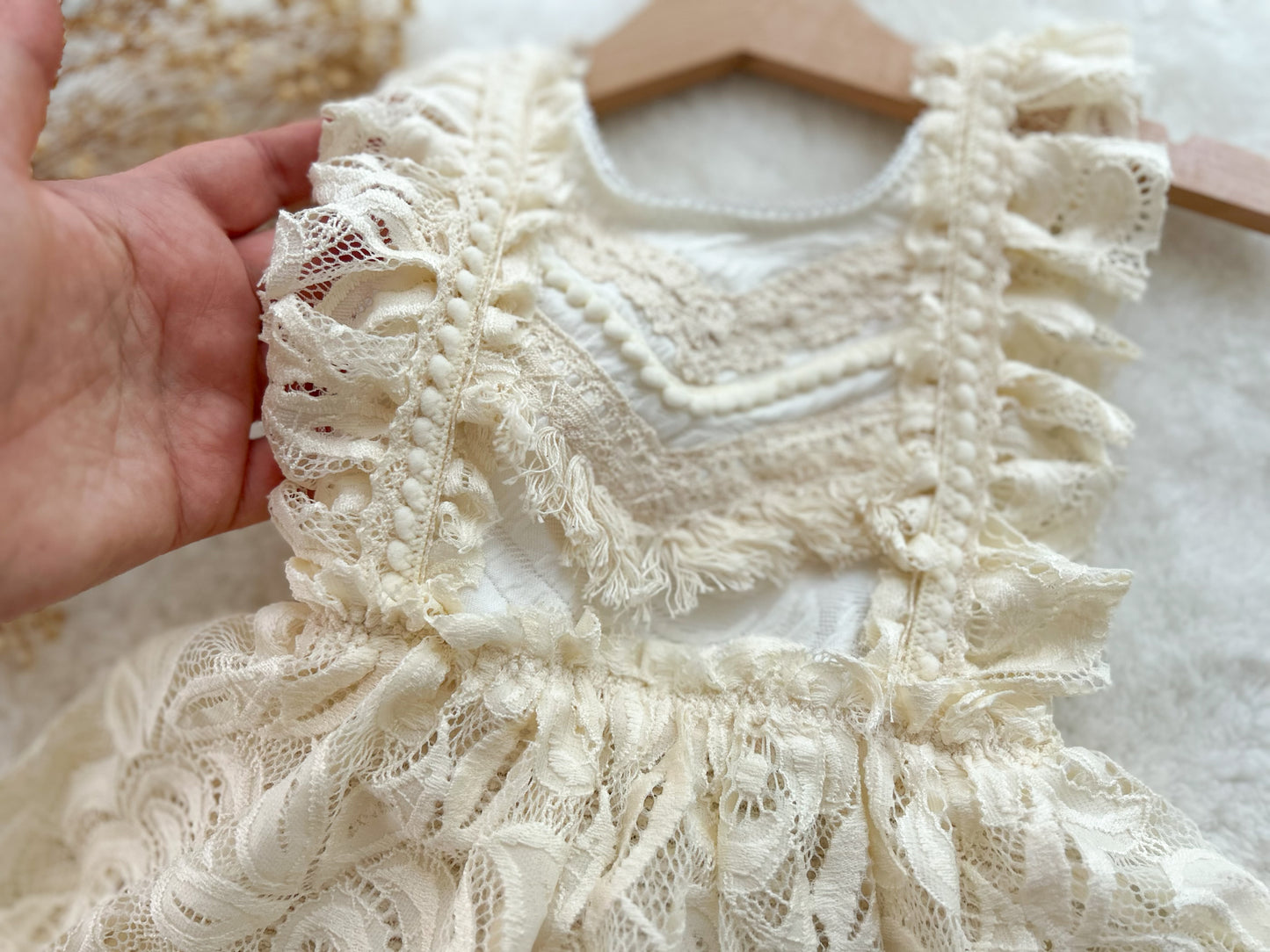 Close-up of a lace dress held by a hand with a blurred background