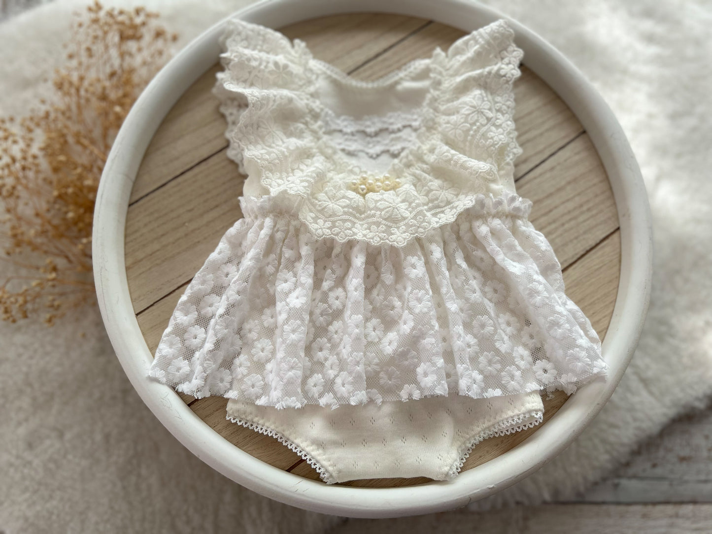 White lace newborn romper and matching posing pillow set on neutral background