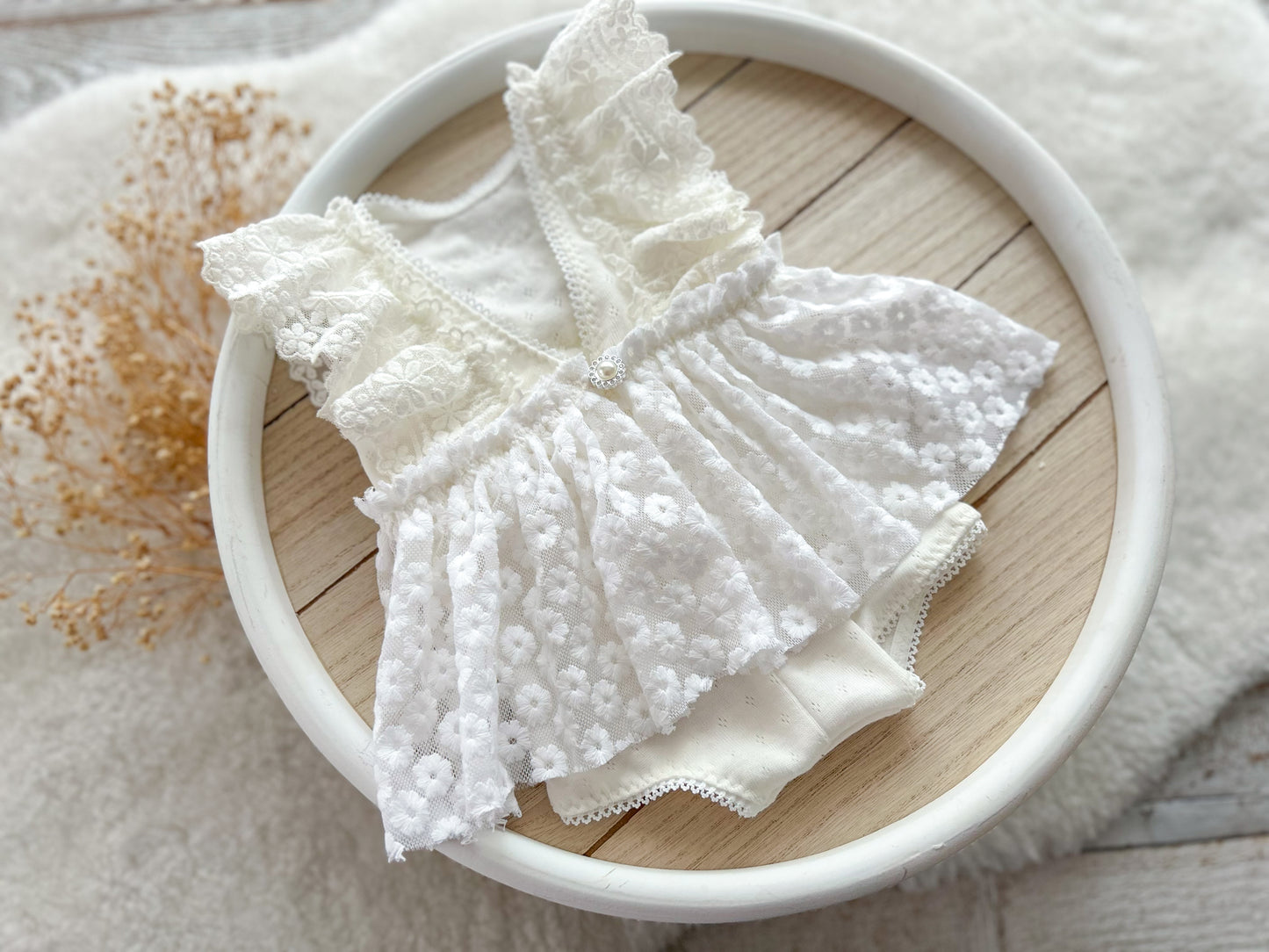 White lace fabric on a wooden surface with a white circular object