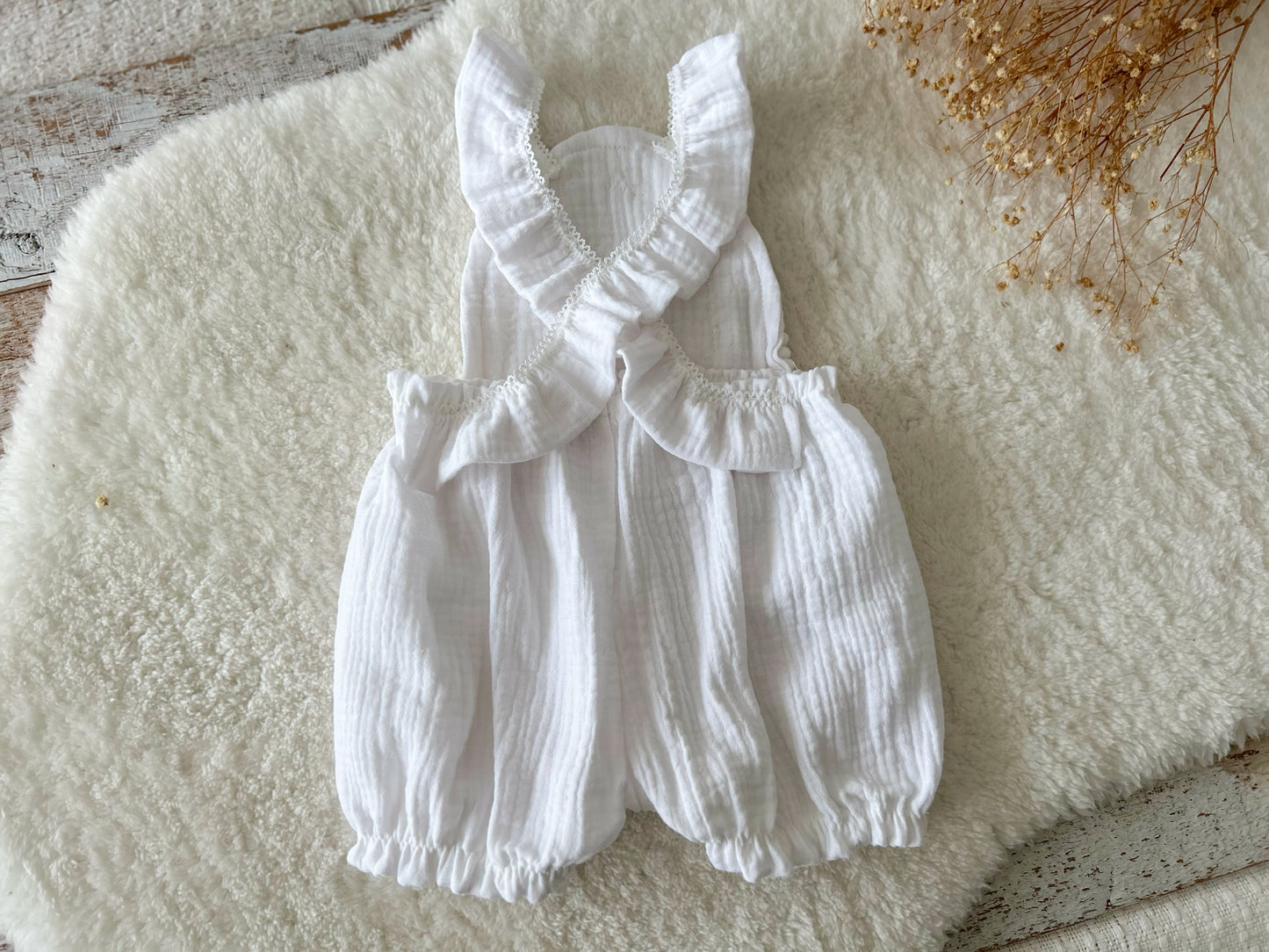 Back view of sitter photo romper made of white muslin fabric with criss crossed straps