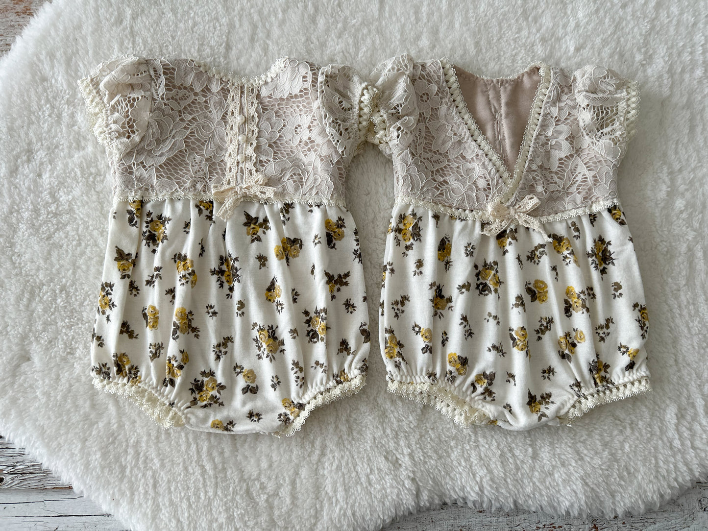 Ivory lace baby romper styled on soft flokati rug – vintage floral prop setup