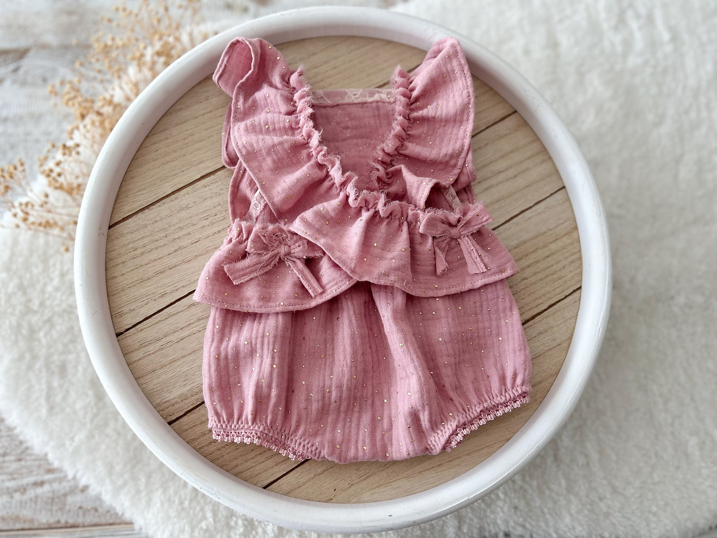 The back of the romper with elasticated ruffles on the back and bow decorations.