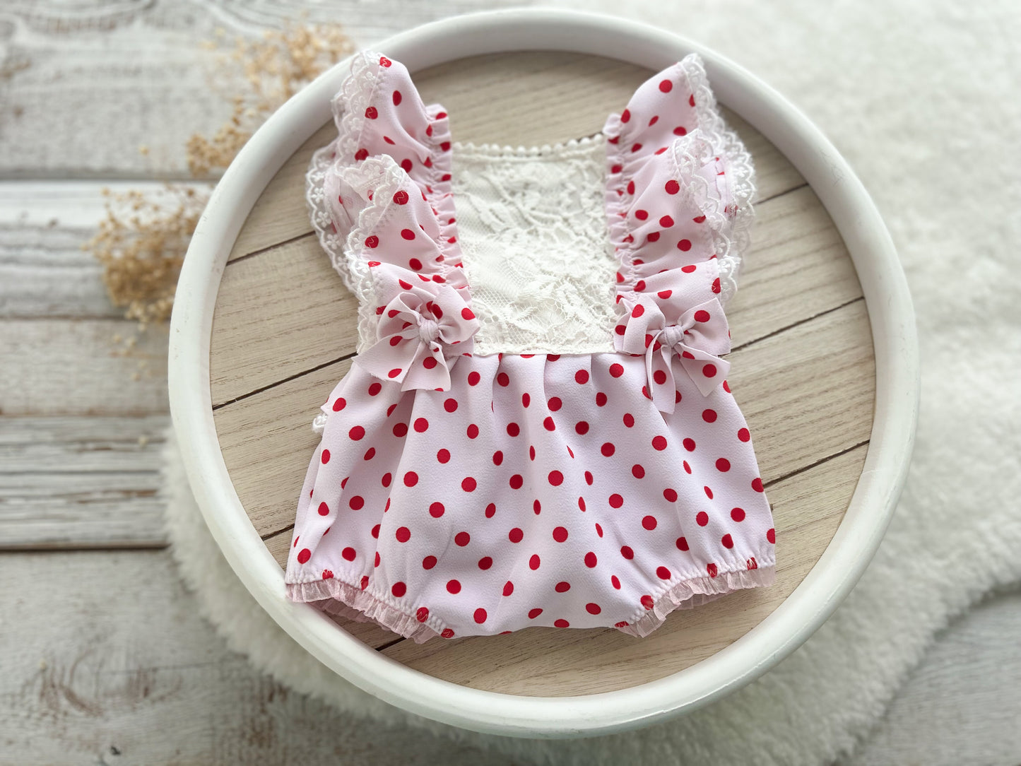 Full view of newborn romper and matching pillow in pink polka dot fabric