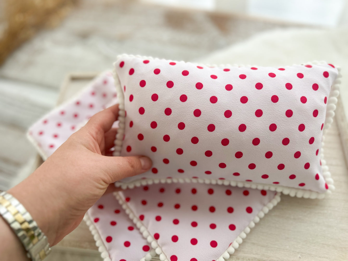 newborn posing pillow with white pompom trim, in light pink with polka dots