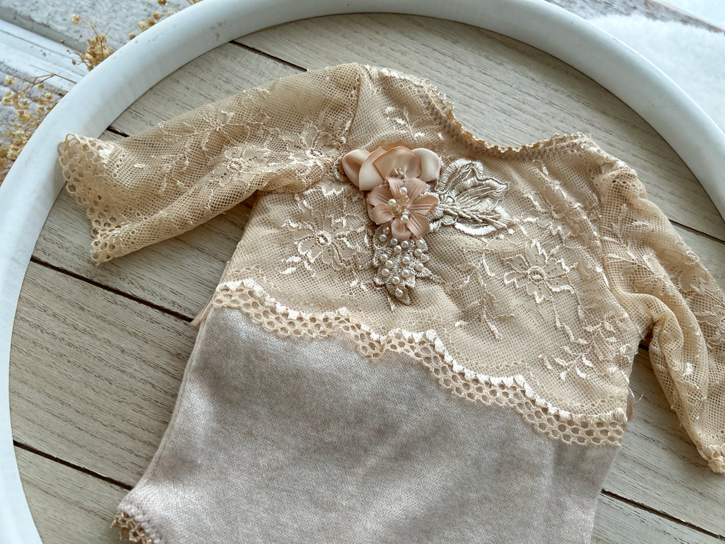 Beige lace baby outfit on a wooden surface