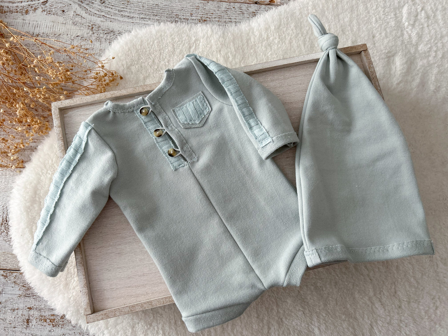 Duck egg blue newborn romper with matching sleepy hat on soft cream background