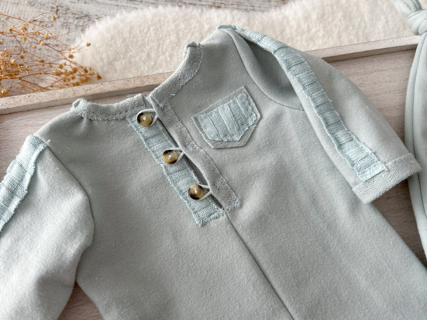 Duck egg blue newborn romper with matching sleepy hat on soft cream background