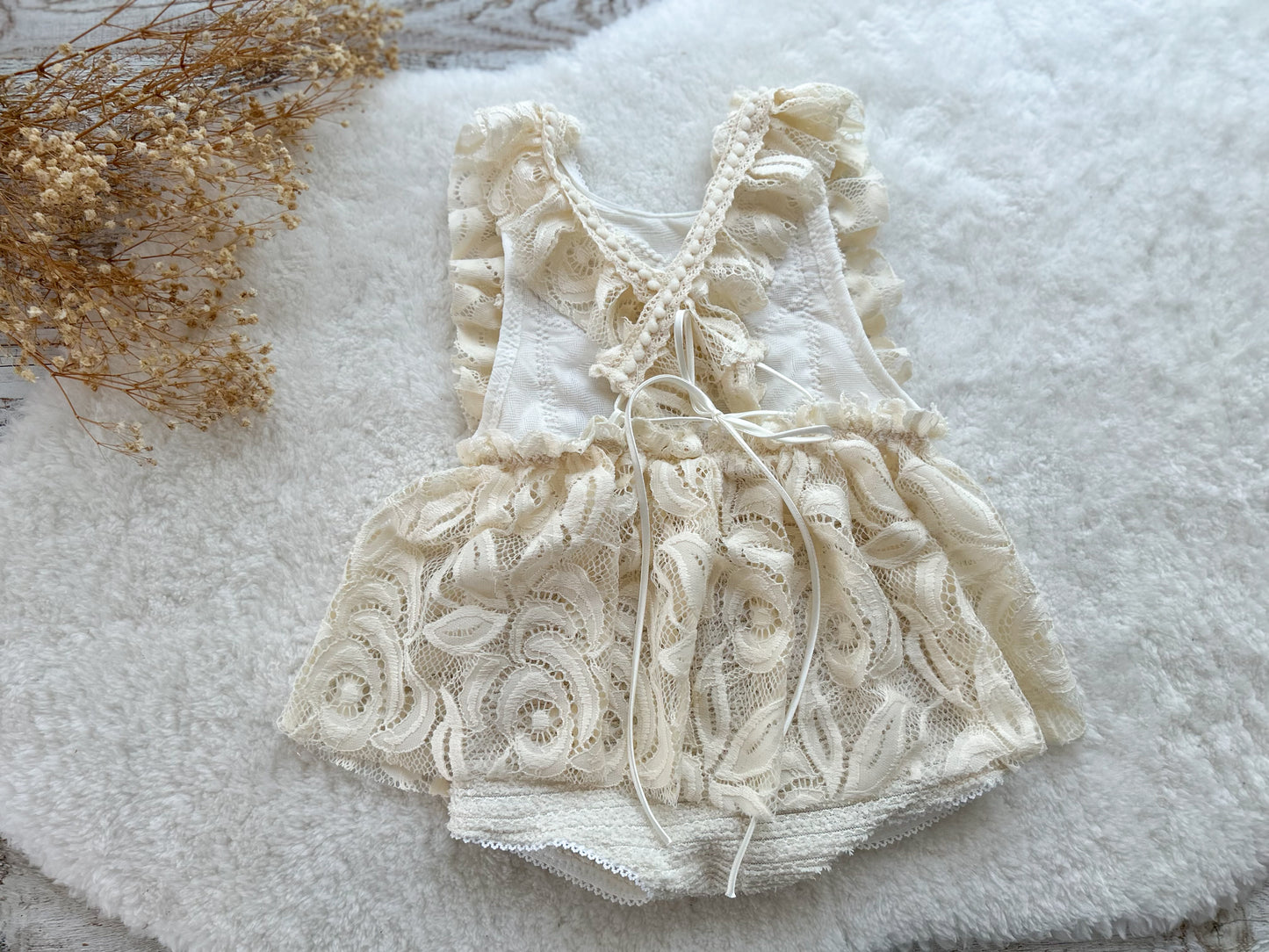 Back view of baby girl romper with criss-cross ruffled straps and a tied bow