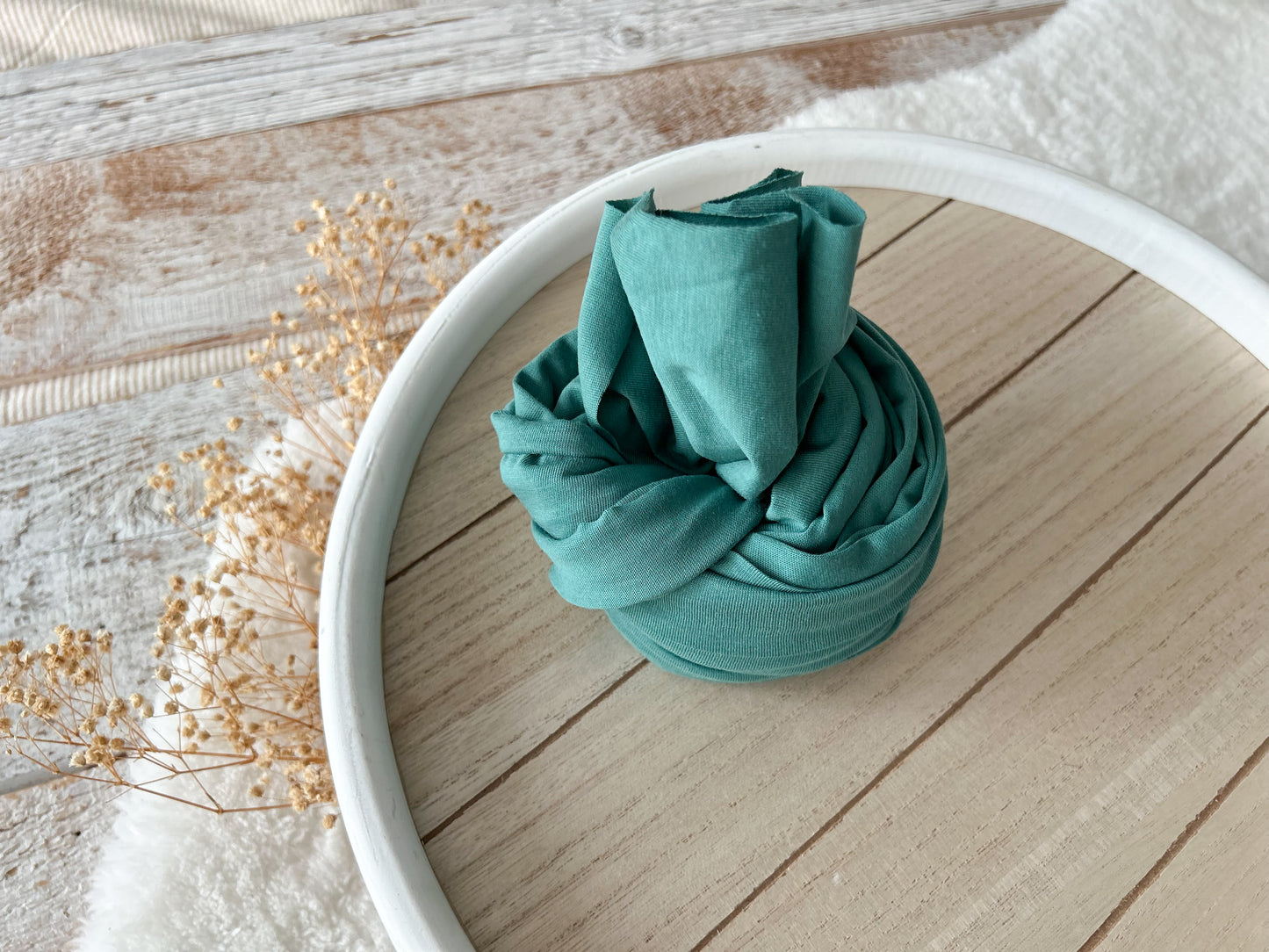 forest green baby photo wrap on a wooden tray