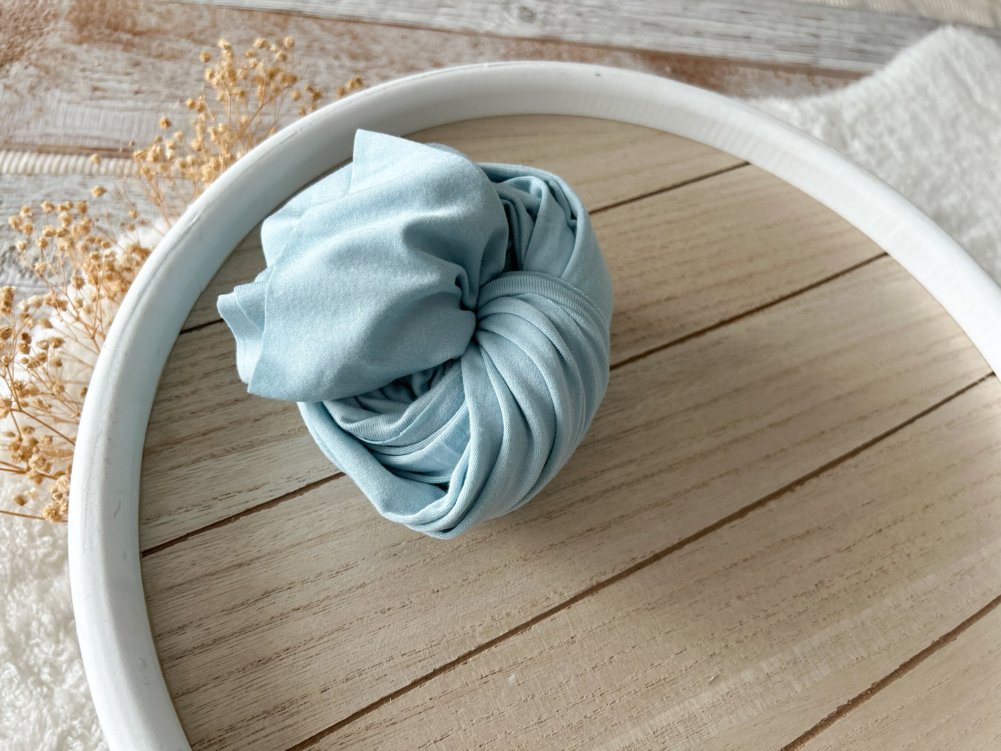 Soft blue stretchy newborn wrap rolled up as a photo prop.
