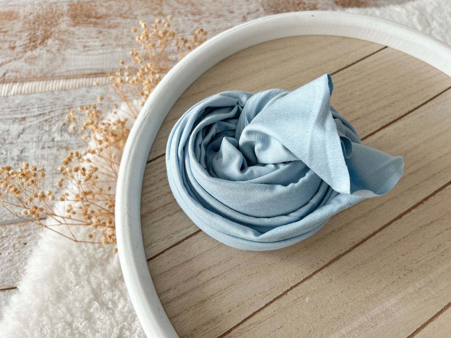Sky blue cotton wrap for newborn photography, rolled and ready for use.