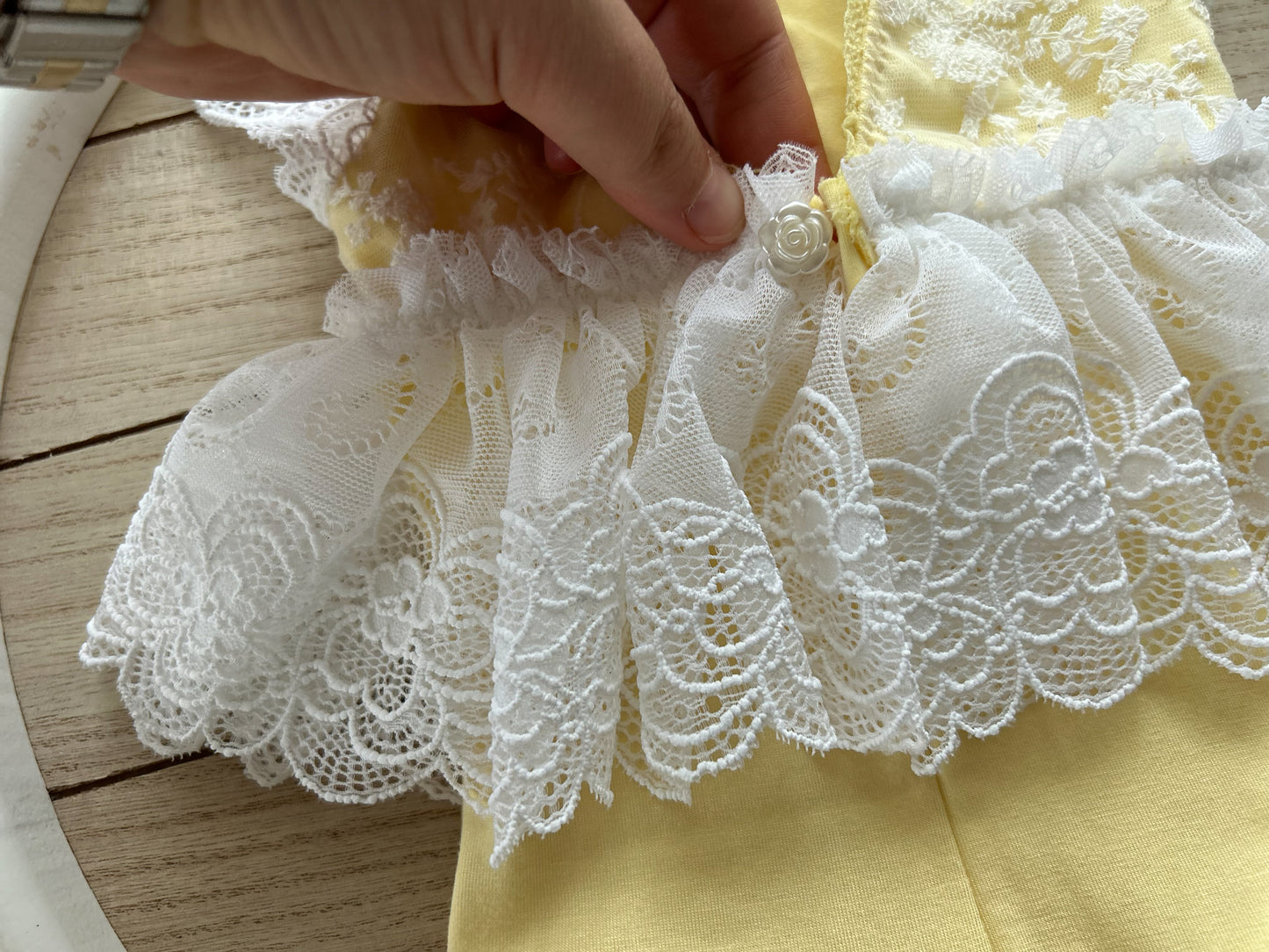 Close-up on the back of the romper with ruffled skirt attached at the waistline and a pearl button closure.