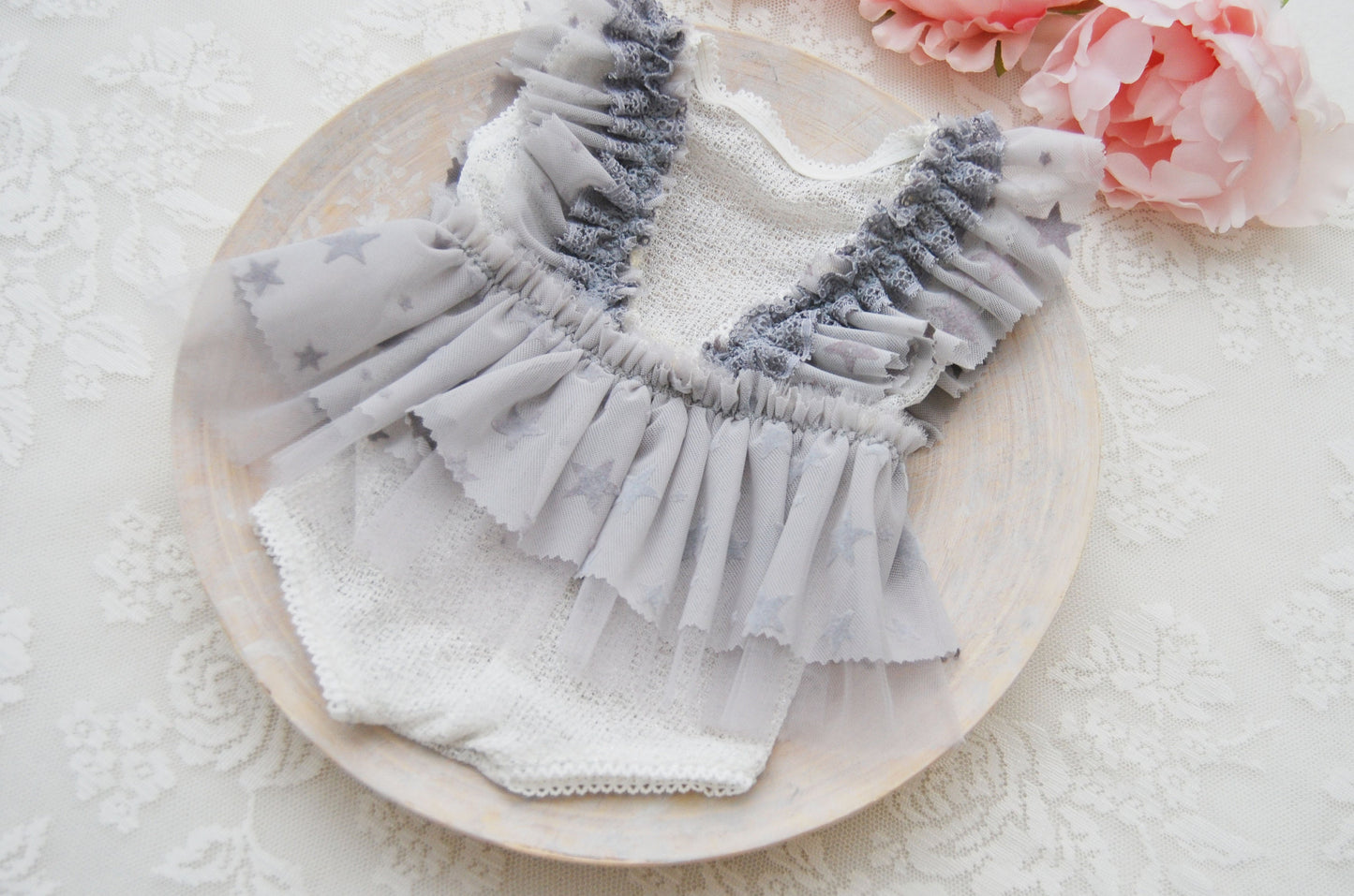 The back of the newborn romper in light gray color with gray ruffles with star pattern.