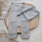 Gray baby outfit with pants and hat on a wooden surface