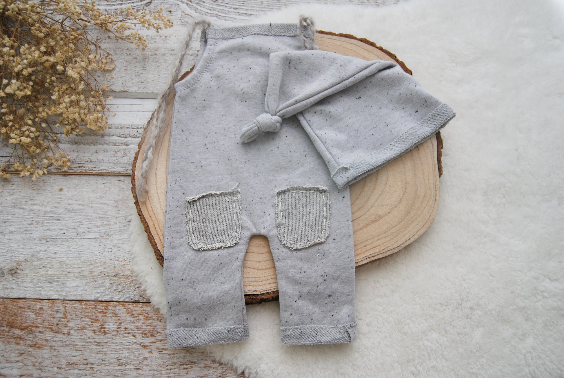 Gray baby outfit with pants and hat on a wooden surface
