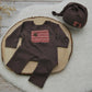 Brown baby outfit with red pocket and matching hat on a wooden surface