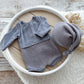 Gray baby outfit with hat in a white bowl on a wooden surface
