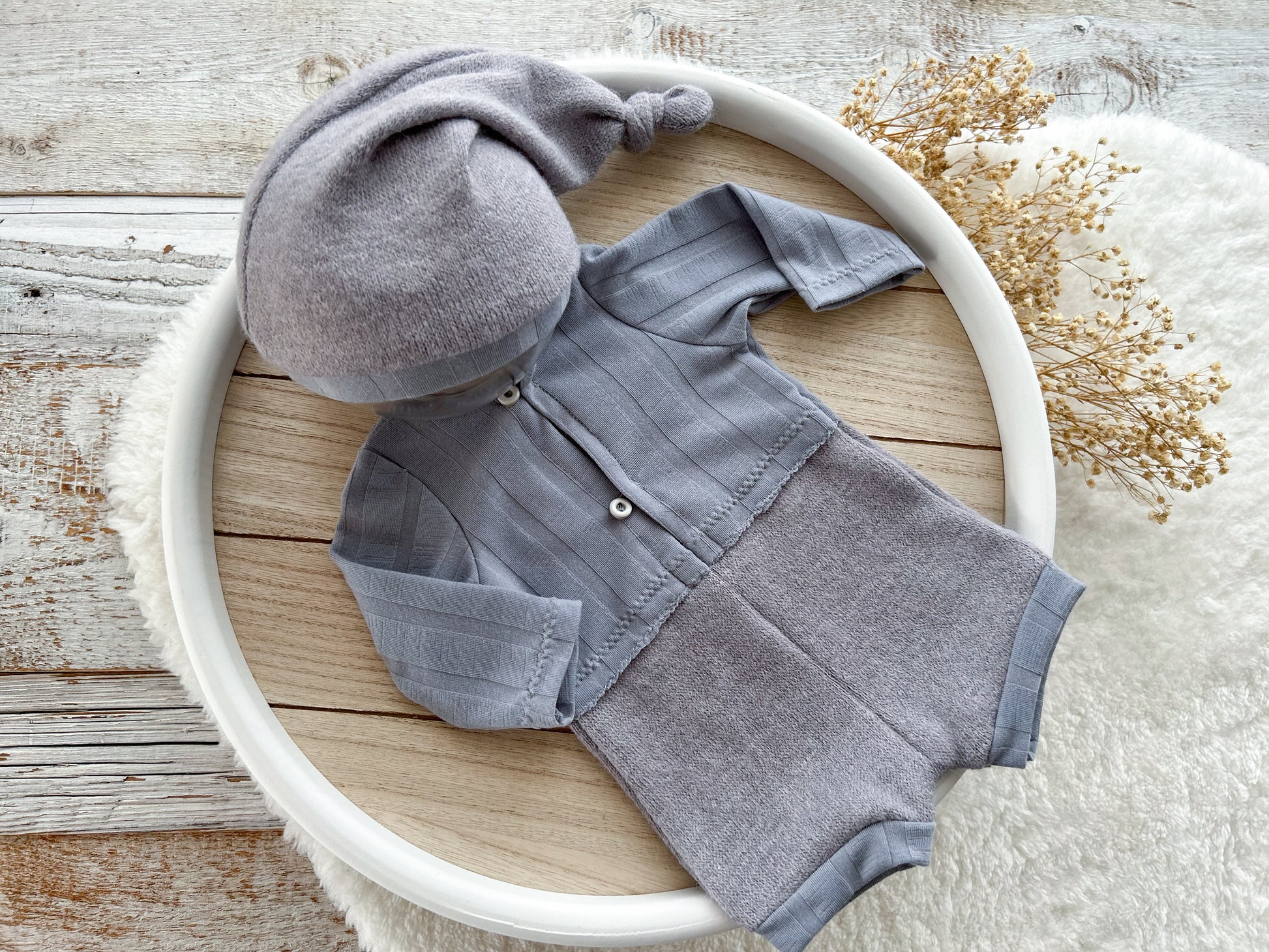 Gray baby outfit with hat on a wooden surface