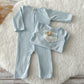 Flat lay of soft blue newborn romper and sleepy hat on fluffy background.