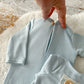 Close-up of front pocket detail on knit romper with wooden button.