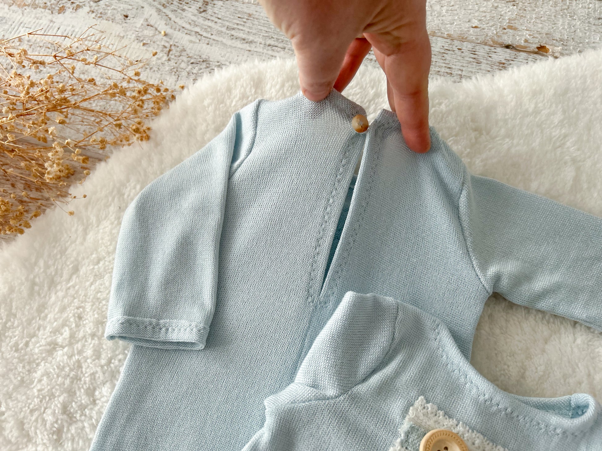 Close-up of front pocket detail on knit romper with wooden button.