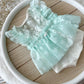 The back of the floral newborn romper in ivory and light mint green with ruffles 
