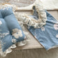 Newborn romper and posing pillow displayed on a wooden tray