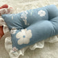 Newborn posing pillow in blue color with white floral pattern and ruffles. 