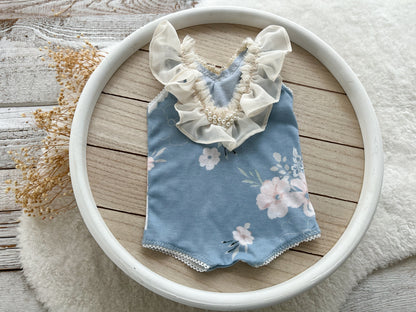 The back of the newborn romper displayed on a round wooden tray.