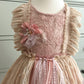 Pink lace dress with floral details on a mannequin against a white background