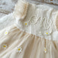 Beige dress with floral details on a wooden surface